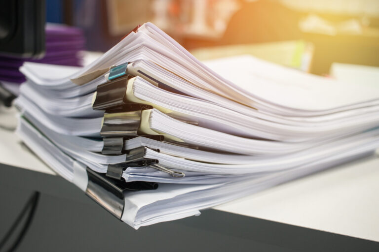 Stack of paper files on work desk in office